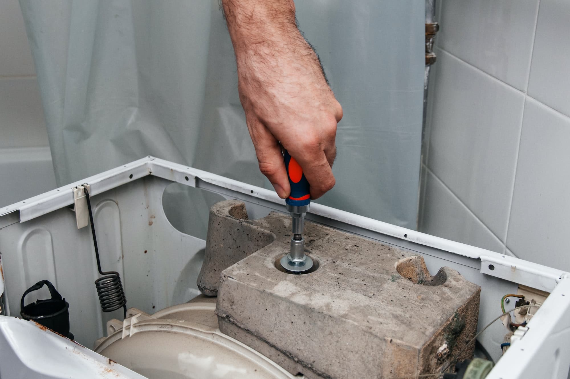 Handyman repairing a washing machine. The hands of a man repair a washing machine.